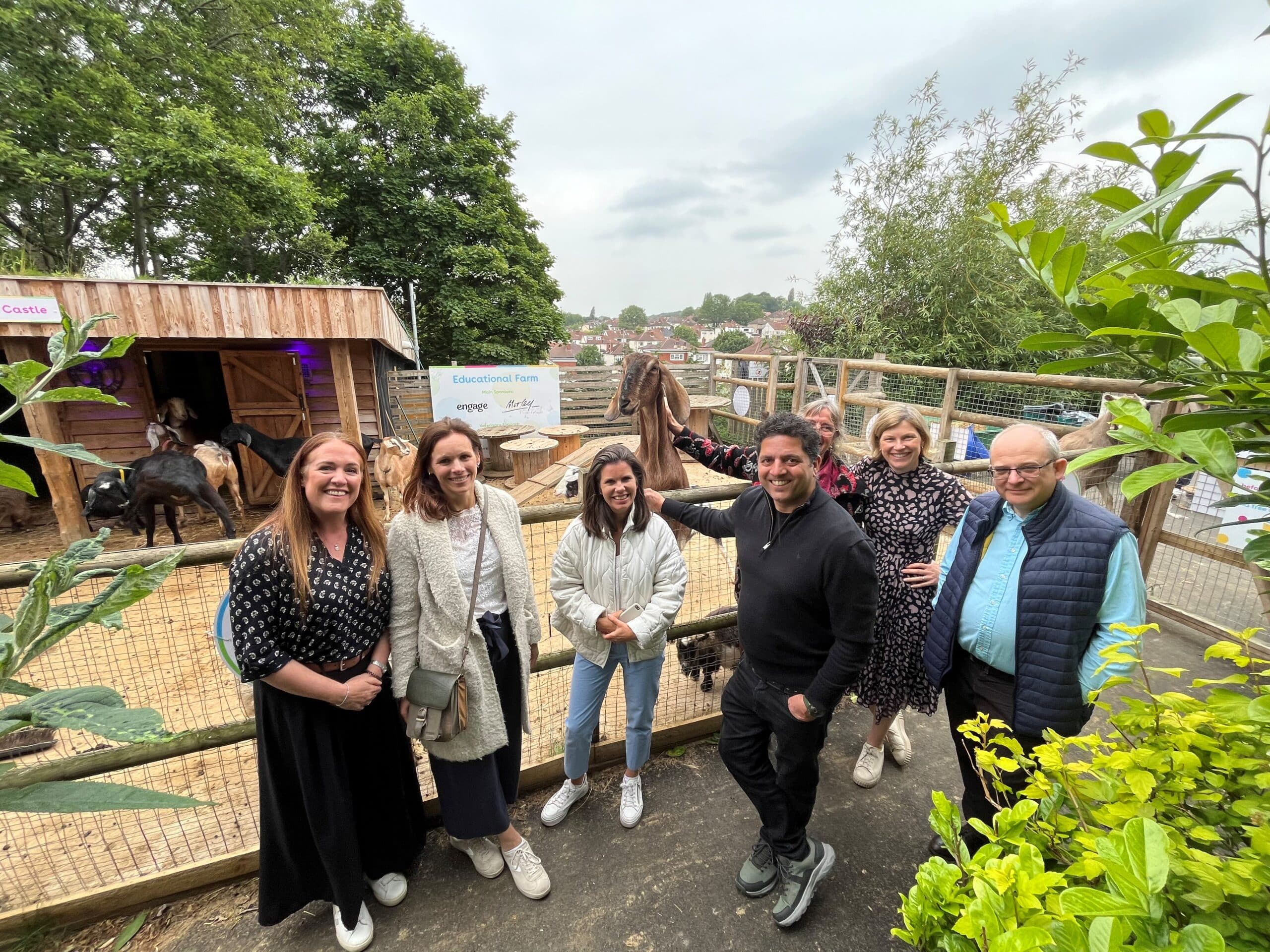 A group of people gathering outdoors in a community garden during a funder visit to CATCH.